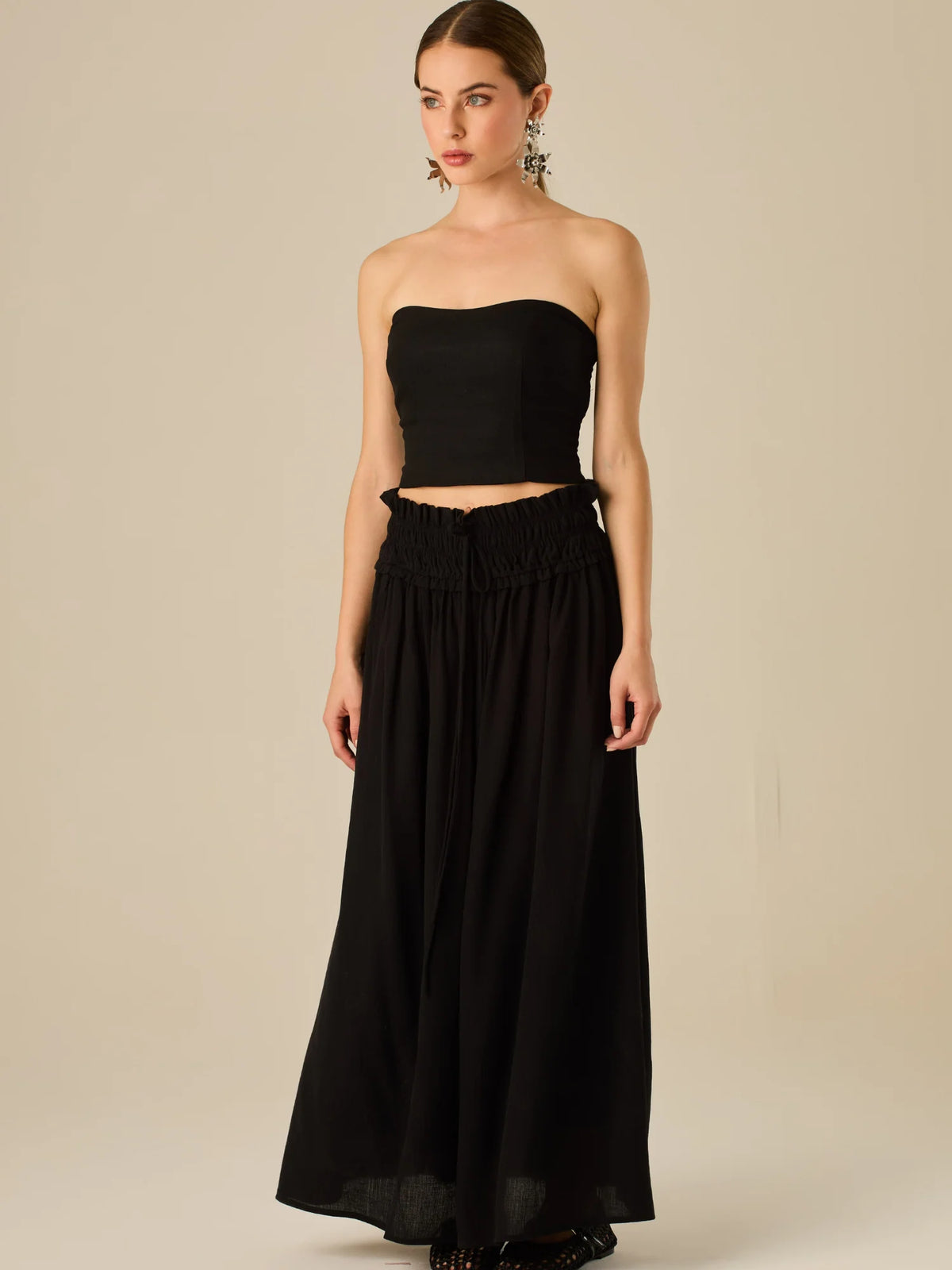 Falda larga de tiro alto con pretina fruncida y lazo ajustable, ideal para un look relajado con elegancia sutil. Su caída fluida y textura ligera aportan movimiento y frescura, perfecta para estilismos sofisticados con esencia natural.

Detalles:

Color: Negro

Material: 82% Rayon 18% Nylon