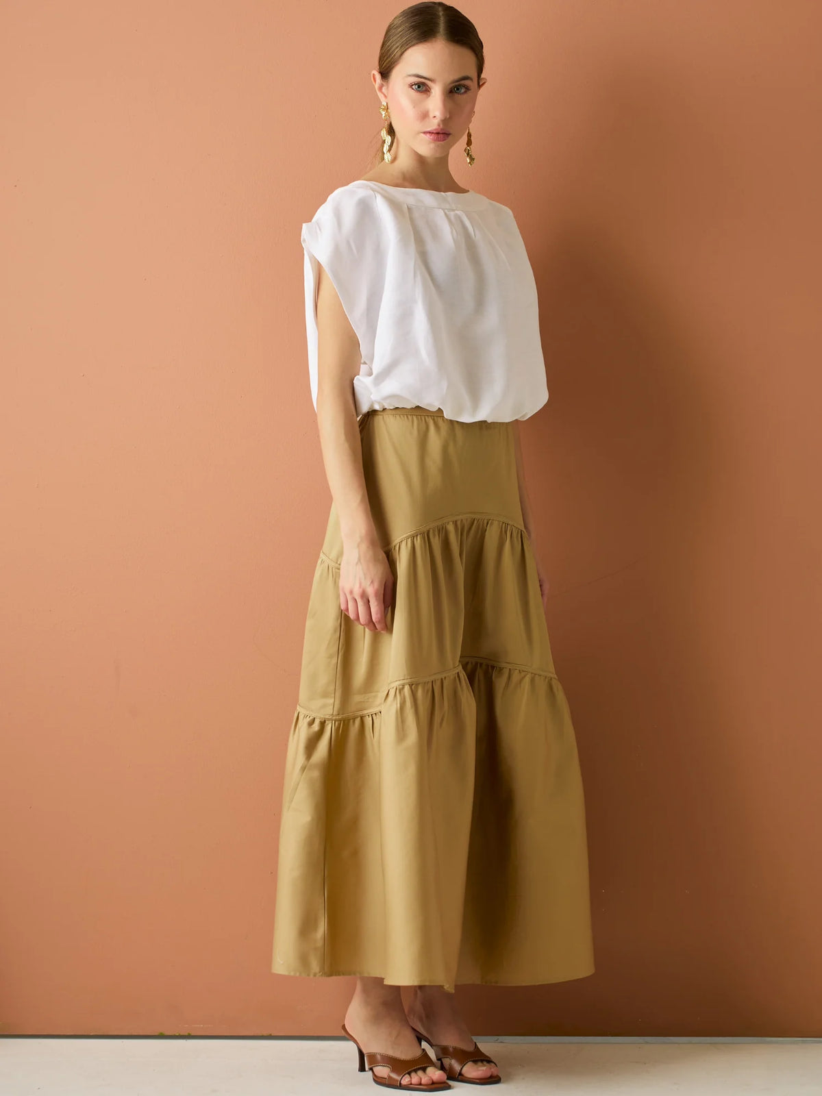 Falda larga con diseño&nbsp; de volantes suaves que aportan movimiento y volumen. Su silueta amplia y estructura liviana la hacen perfecta para un look relajado y sofisticado, ideal para combinar con blusas ligeras y crear estilismos con encanto natural.

Detalles:

Color: Camel