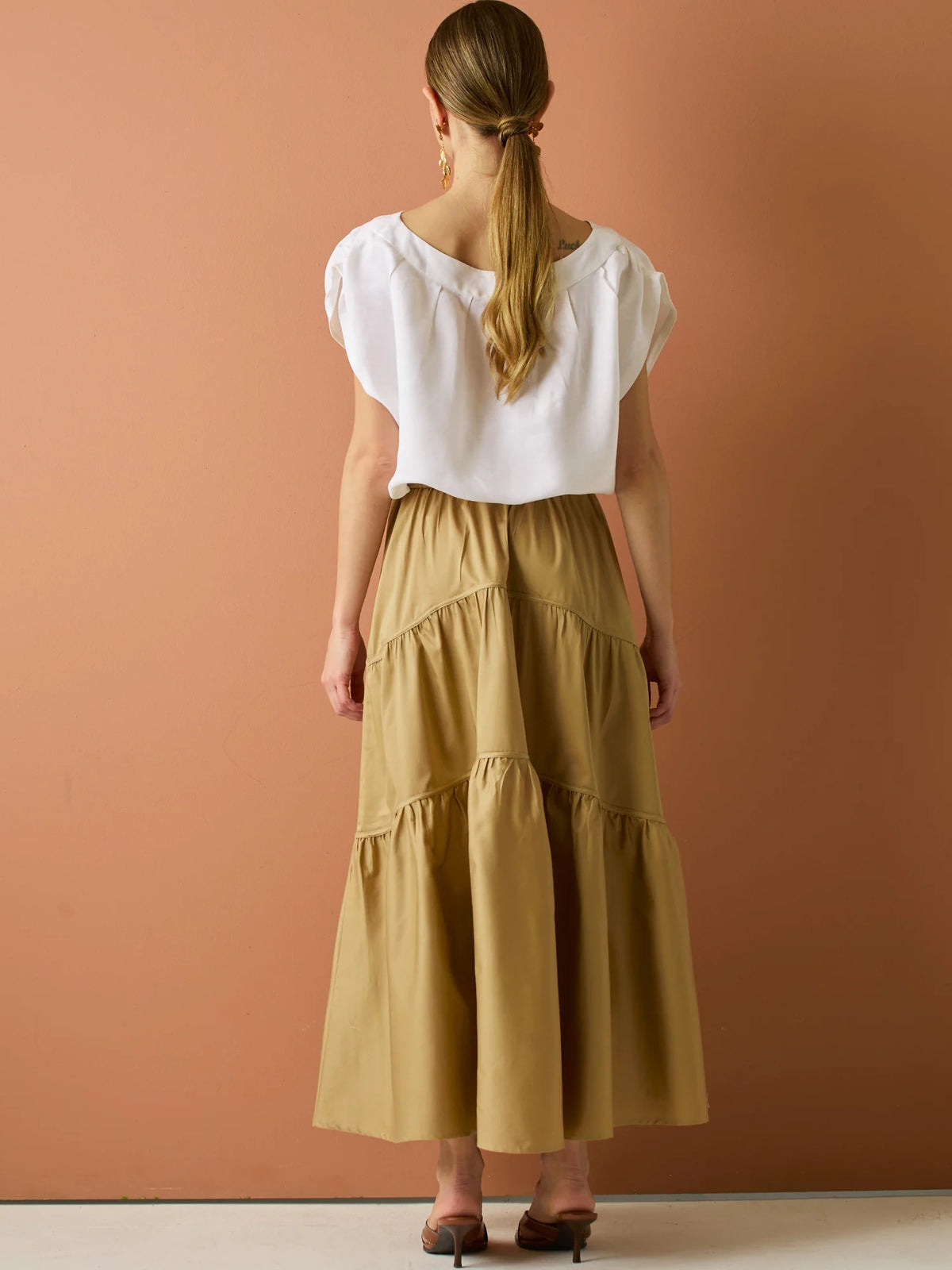 Falda larga con diseño&nbsp; de volantes suaves que aportan movimiento y volumen. Su silueta amplia y estructura liviana la hacen perfecta para un look relajado y sofisticado, ideal para combinar con blusas ligeras y crear estilismos con encanto natural.

Detalles:

Color: Camel