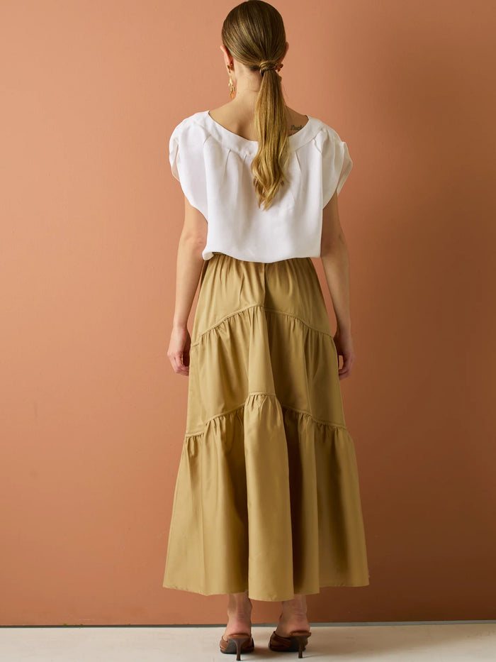 Falda larga con diseño&nbsp; de volantes suaves que aportan movimiento y volumen. Su silueta amplia y estructura liviana la hacen perfecta para un look relajado y sofisticado, ideal para combinar con blusas ligeras y crear estilismos con encanto natural.

Detalles:

Color: Camel