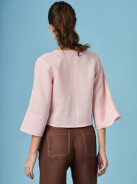 Blusa rosa moderna diseñada para estilizar el torso gracias a su escote en V y corte cruzado. Una prenda clave para crear outfits armoniosos y femeninos.