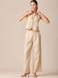 Pantalón de tiro medio con pretina plana, pinzas frontales y corte recto amplio hasta el tobillo, confeccionado en un tejido liviano de textura natural que aporta un look sofisticado y relajado