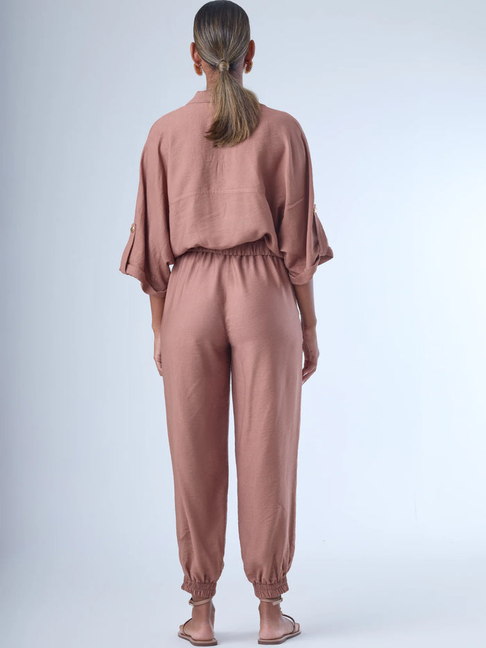 Cómodo y versátil, este pantalón tipo jogger presenta una silueta relajada con ajuste en tobillos y cintura elástica para máximo confort. Los bolsillos frontales tipo parche y la textura suave de la tela lo hacen ideal para looks casuales con un toque elevado. Perfecto para combinar con blusas fluidas o camisas estructuradas, en días de descanso o estilismos urbanos sofisticados.