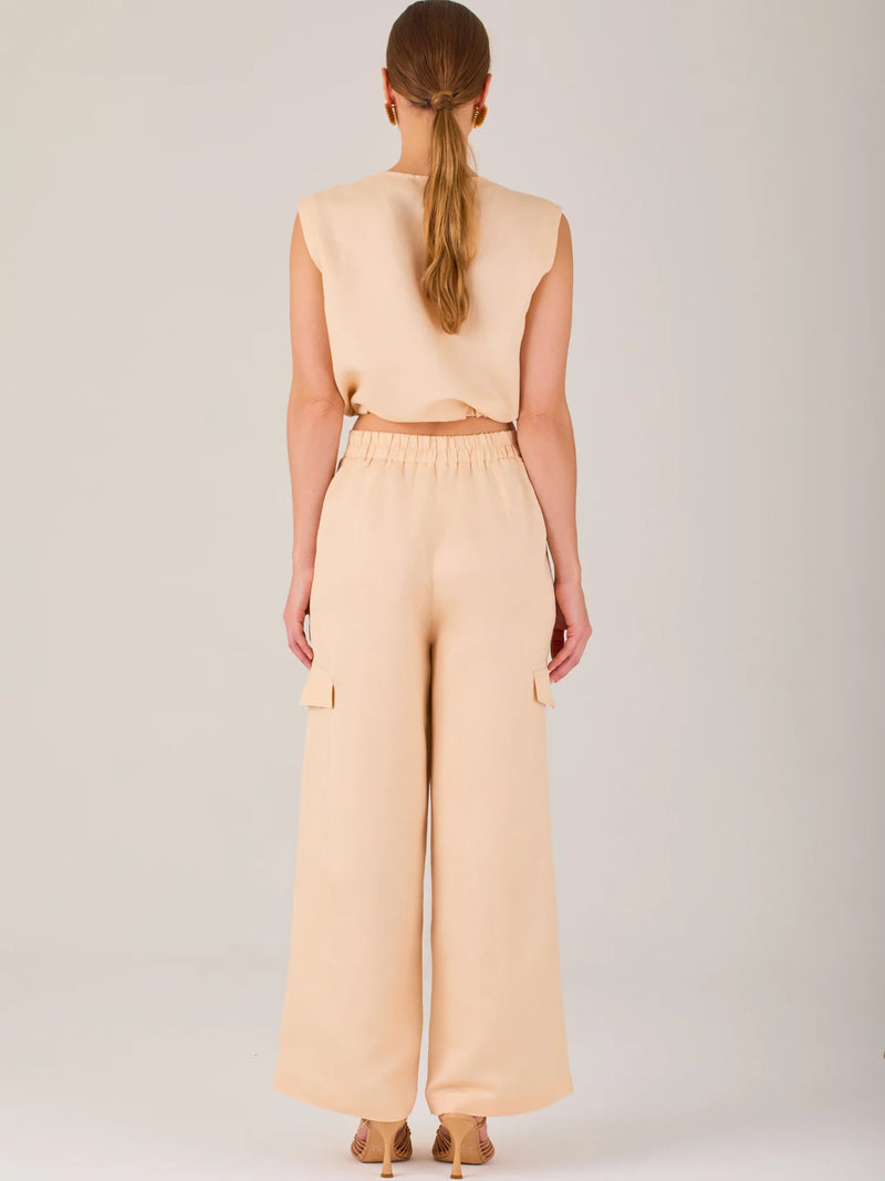 Este pantalón de corte recto y silueta ancha tiene un diseño tipo cargo, con bolsillos de solapa a los costados de las piernas que aportan un toque utilitario. La pretina combina funcionalidad y estilo: es parcialmente elástica en la parte posterior para mayor comodidad, mientras que el frente incluye cierre con botón y pinzas que añaden estructura. Su diseño equilibra lo casual y lo sofisticado, ideal para looks versátiles.