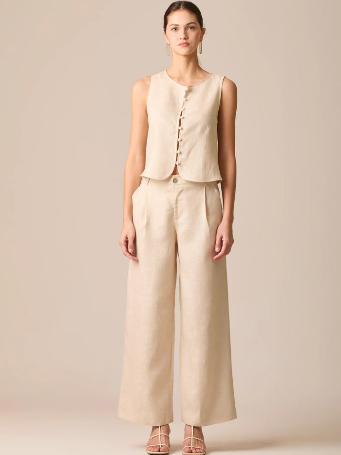 Pantalón de tiro medio con pretina plana, pinzas frontales y corte recto amplio hasta el tobillo, confeccionado en un tejido liviano de textura natural que aporta un look sofisticado y relajado