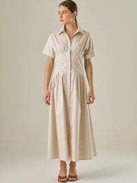 Vestido camisero midi con mangas cortas y falda amplia, ideal para un look elegante y relajado. Su diseño con pinzas en el busto realza la figura con sutileza, mientras que los botones al frente aportan un toque clásico y versátil.

Detalles:

Color: Sand

Material: 97% Algodón 3% Spandex