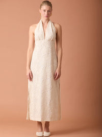 Vestido largo beige con cuello halter y textura en relieve, ideal para ocasiones elegantes.