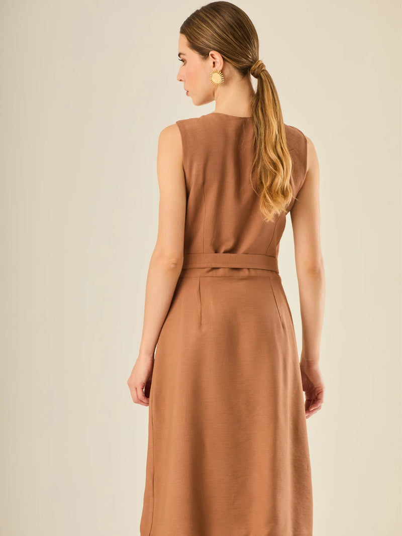 Vestido sin mangas con botonadura frontal y cinturón a tono con hebilla dorada. Tiene bolsillos tipo parche en el pecho y la cadera que acentúan su aire utilitario, mientras que el largo midi y los botones metálicos le dan un acabado elegante y atemporal. Perfecto para un look sofisticado de día.
