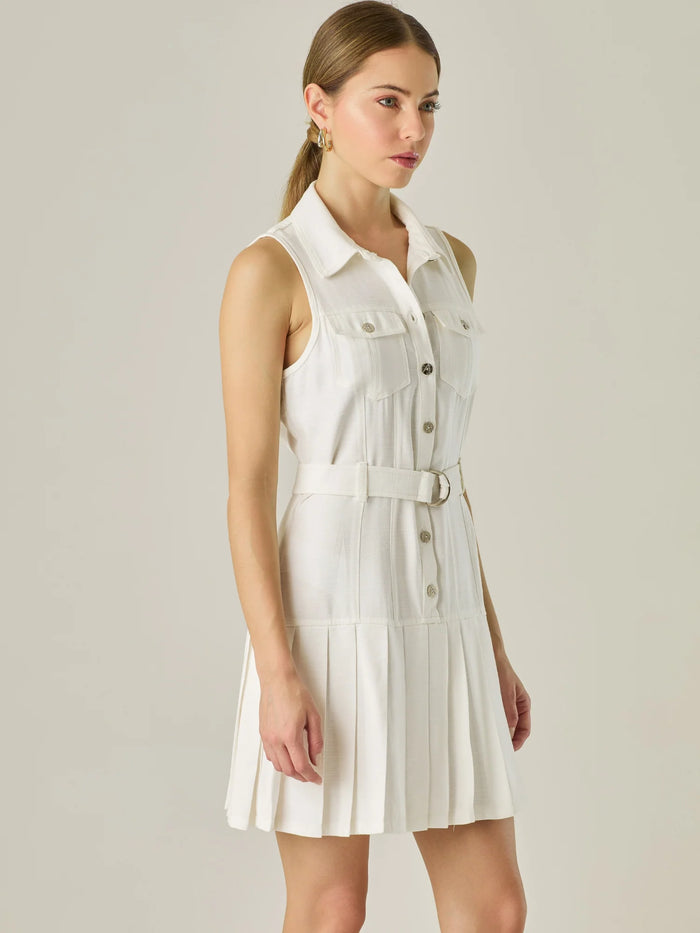 Vestido corto sin mangas con estructura camisera, bolsillos frontales y falda plisada que aporta movimiento y estilo. El cinturón ajustable realza la silueta, logrando un look casual con un toque sofisticado, ideal para días activos con mucho estilo.

Detalles:

Color: Blanco Perla

Material: 93% Rayón 7% Poliéster

Características: Incluye cinturón a tono .