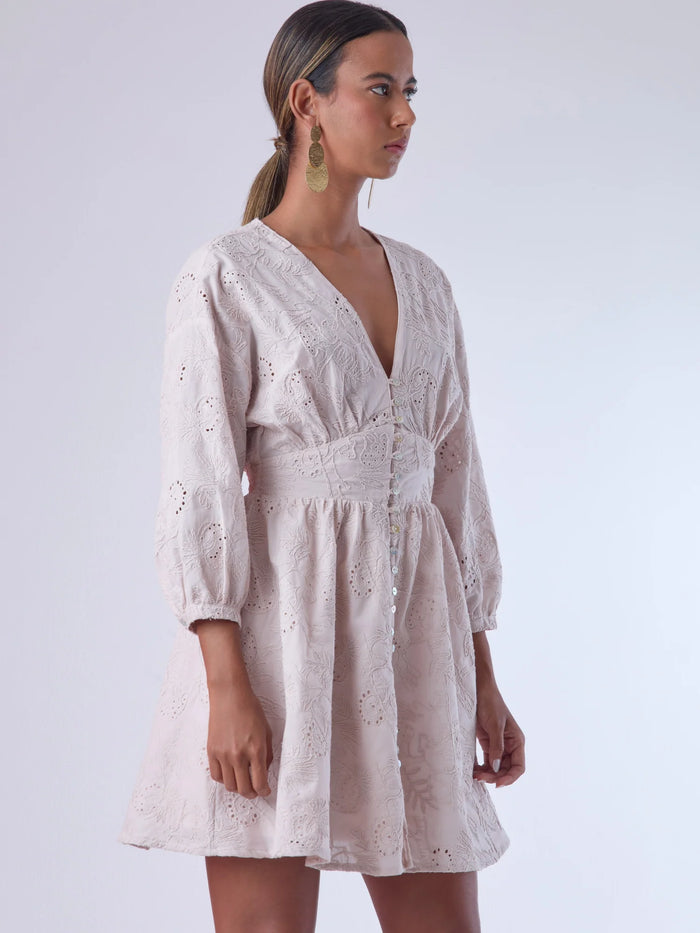 Este vestido de silueta femenina combina un escote en V profundo con una cintura marcada que estiliza la figura. Con mangas 3/4 ligeramente abullonadas y delicados detalles bordados, es una prenda ideal para ocasiones especiales de día o eventos semi formales. Su botonadura frontal añade un toque romántico y clásico que realza su diseño atemporal.