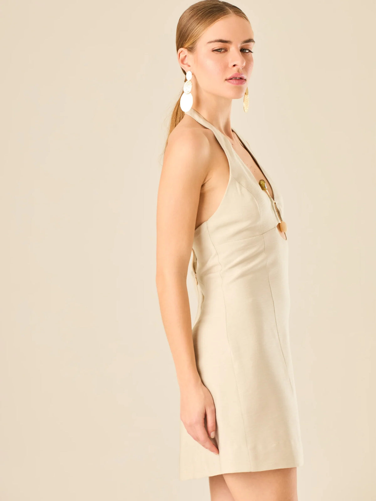 Vestido corto en tono crema de silueta ajustada con escote halter profundo que se adorna con un original detalle de argollas decorativas en el centro del busto, creando un sutil efecto de abertura. Su diseño minimalista con acento sensual lo convierte en una prenda ideal para ocasiones especiales con un toque moderno y sofisticado.

Color: Cemento

Material: 92% Rayon 8% poliester

Características: Incluye hebilla.