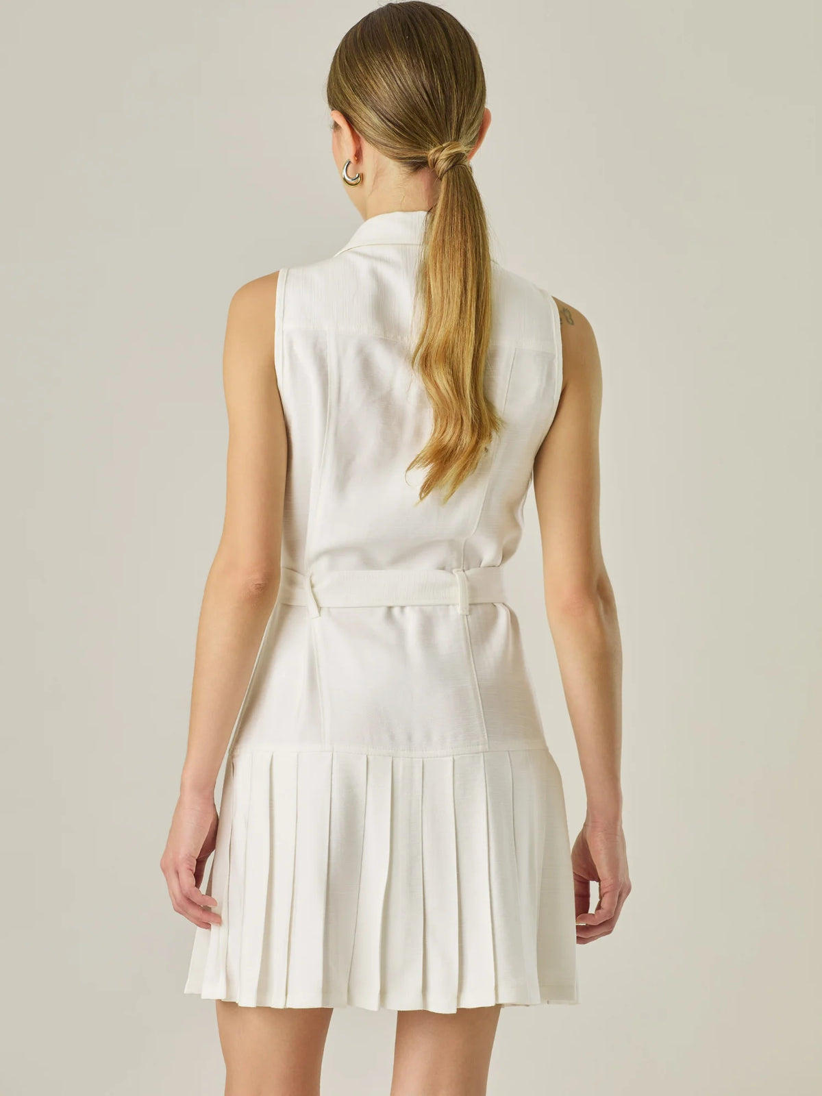 Vestido corto sin mangas con estructura camisera, bolsillos frontales y falda plisada que aporta movimiento y estilo. El cinturón ajustable realza la silueta, logrando un look casual con un toque sofisticado, ideal para días activos con mucho estilo.

Detalles:

Color: Blanco Perla

Material: 93% Rayón 7% Poliéster

Características: Incluye cinturón a tono .