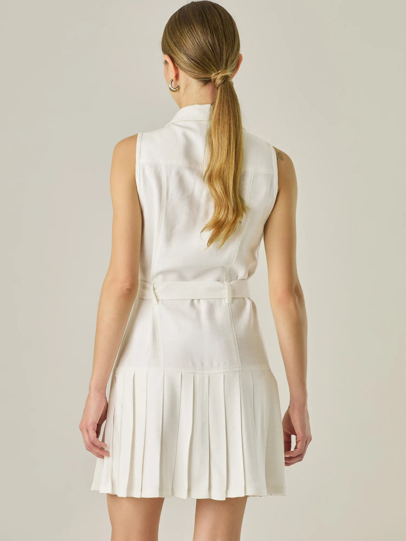 Vestido corto sin mangas con estructura camisera, bolsillos frontales y falda plisada que aporta movimiento y estilo. El cinturón ajustable realza la silueta, logrando un look casual con un toque sofisticado, ideal para días activos con mucho estilo.

Detalles:

Color: Blanco Perla

Material: 93% Rayón 7% Poliéster

Características: Incluye cinturón a tono .