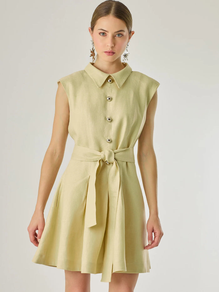 Vestido corto sin mangas con botones frontales y cuello camisero, complementado con un lazo que define la cintura. Su diseño sencillo y femenino lo convierte en una opción ideal para un look casual con un aire sofisticado y fresco.

Color: Vainilla

Material: Lino