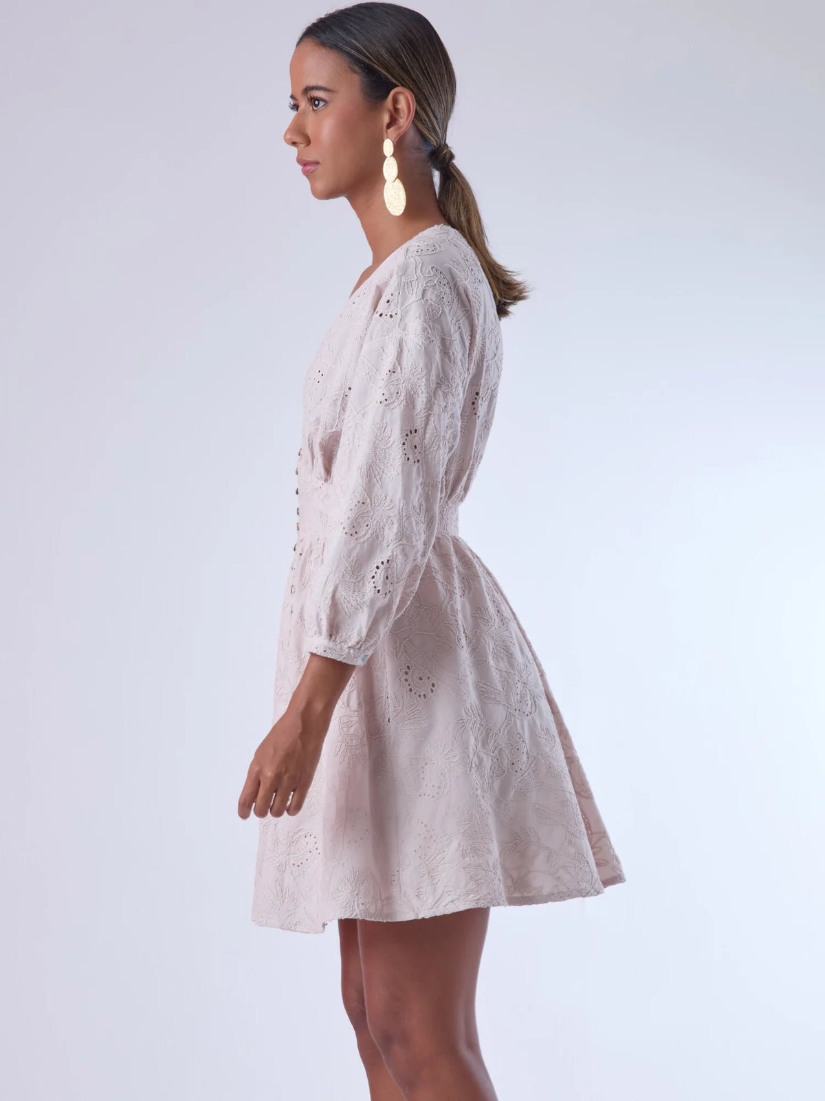 Este vestido de silueta femenina combina un escote en V profundo con una cintura marcada que estiliza la figura. Con mangas 3/4 ligeramente abullonadas y delicados detalles bordados, es una prenda ideal para ocasiones especiales de día o eventos semi formales. Su botonadura frontal añade un toque romántico y clásico que realza su diseño atemporal.