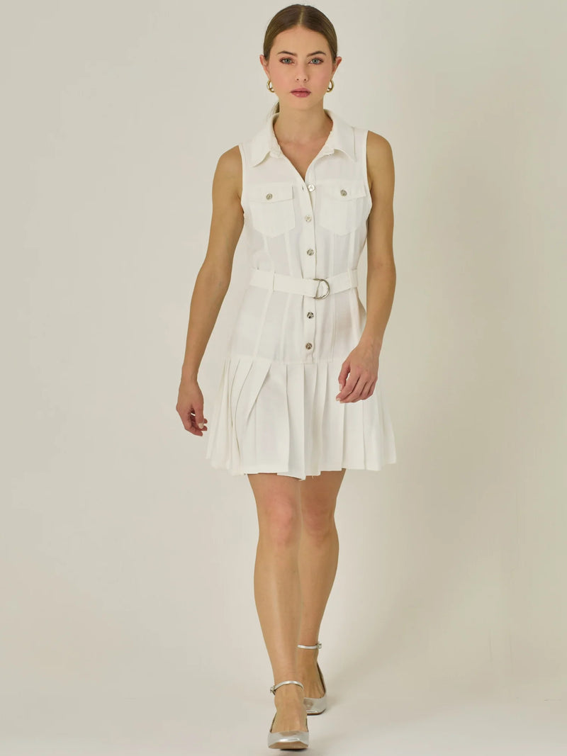 Vestido corto sin mangas con estructura camisera, bolsillos frontales y falda plisada que aporta movimiento y estilo. El cinturón ajustable realza la silueta, logrando un look casual con un toque sofisticado, ideal para días activos con mucho estilo.

Detalles:

Color: Blanco Perla

Material: 93% Rayón 7% Poliéster

Características: Incluye cinturón a tono .