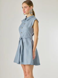 Vestido corto sin mangas con botones frontales y cuello camisero, complementado con un lazo que define la cintura. Su diseño sencillo y femenino lo convierte en una opción ideal para un look casual con un aire sofisticado y fresco.

Color: Indigo

Material: Lino

Características: Incluye cinturón a tono.