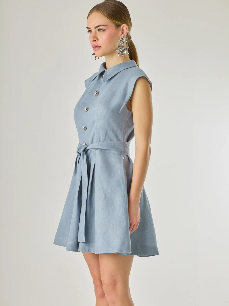 Vestido corto sin mangas con botones frontales y cuello camisero, complementado con un lazo que define la cintura. Su diseño sencillo y femenino lo convierte en una opción ideal para un look casual con un aire sofisticado y fresco.

Color: Indigo

Material: Lino

Características: Incluye cinturón a tono.