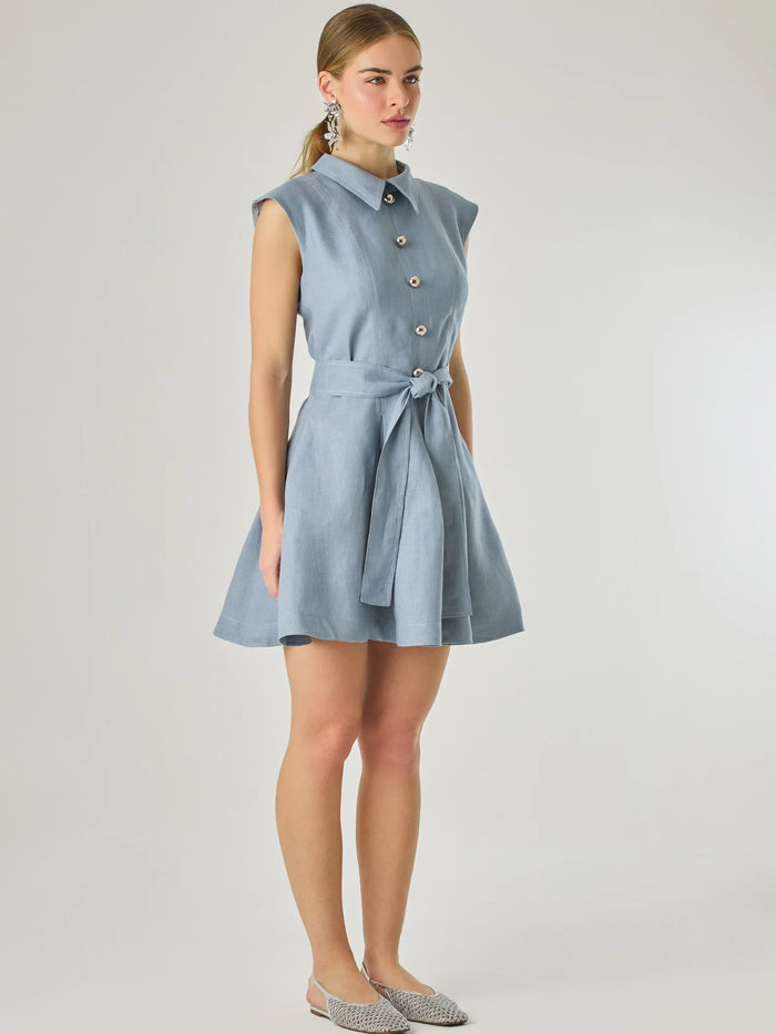 Vestido corto sin mangas con botones frontales y cuello camisero, complementado con un lazo que define la cintura. Su diseño sencillo y femenino lo convierte en una opción ideal para un look casual con un aire sofisticado y fresco.

Color: Indigo

Material: Lino

Características: Incluye cinturón a tono.