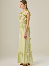 Vestido largo sin mangas con escote en "V" profundo y un diseño con volantes que recorren tanto los tirantes como la parte frontal del busto y la falda. La cintura está fruncida con elástico para dar definición y comodidad, mientras que la falda fluye suavemente con un detalle de volante en el dobladillo, aportando movimiento y un aire femenino al conjunto.