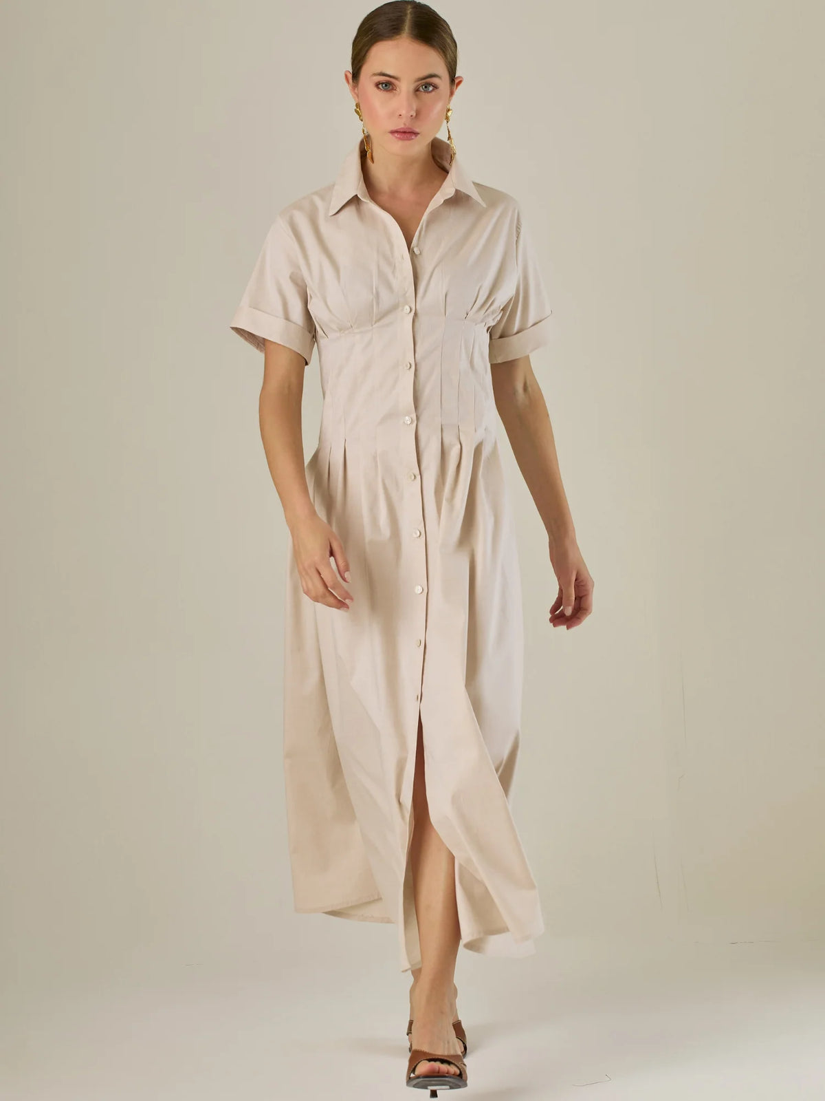 Vestido camisero midi con mangas cortas y falda amplia, ideal para un look elegante y relajado. Su diseño con pinzas en el busto realza la figura con sutileza, mientras que los botones al frente aportan un toque clásico y versátil.

Detalles:

Color: Sand

Material: 97% Algodón 3% Spandex