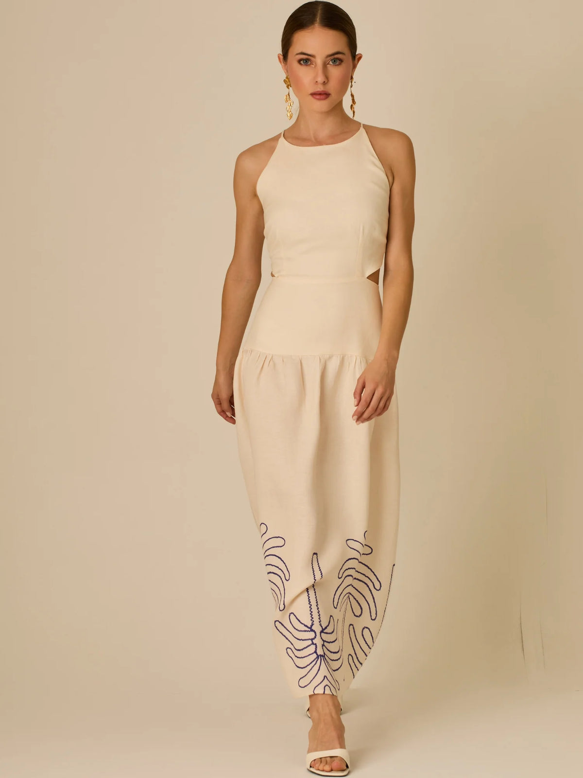 Vestido largo sin mangas con escote recto, aberturas laterales y detalle bordado en el bajo con motivos de inspiración natural. Su diseño limpio y femenino lo convierte en una opción ideal para un look sofisticado con un aire fresco y artesanal.

Detalles:

Color: Sand

Materia: 52% Lino 48% Rayon