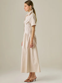 Vestido camisero midi con mangas cortas y falda amplia, ideal para un look elegante y relajado. Su diseño con pinzas en el busto realza la figura con sutileza, mientras que los botones al frente aportan un toque clásico y versátil.

Detalles:

Color: Sand

Material: 97% Algodón 3% Spandex