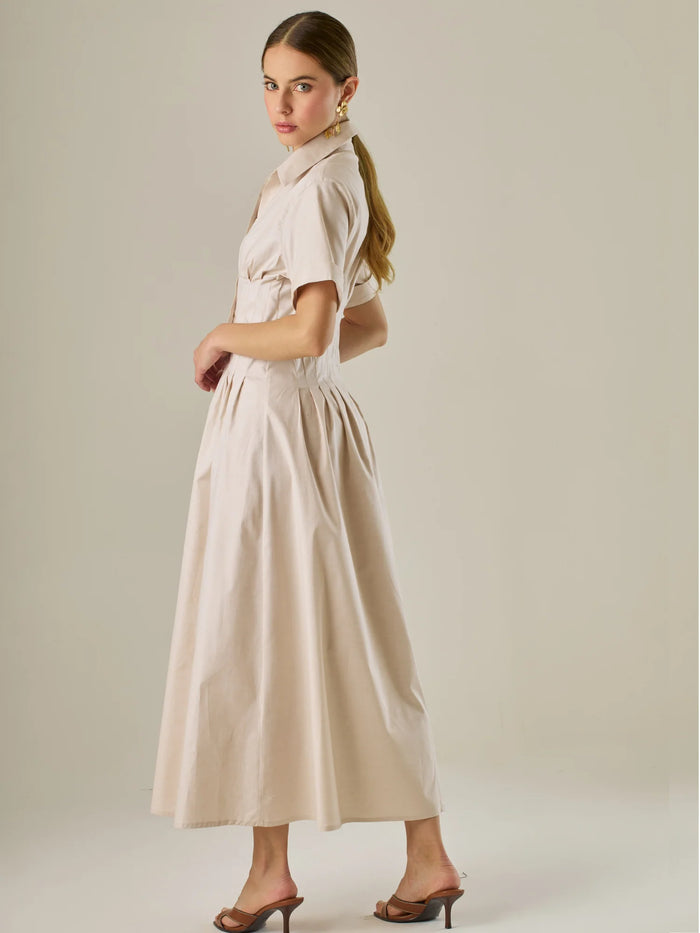 Vestido camisero midi con mangas cortas y falda amplia, ideal para un look elegante y relajado. Su diseño con pinzas en el busto realza la figura con sutileza, mientras que los botones al frente aportan un toque clásico y versátil.

Detalles:

Color: Sand

Material: 97% Algodón 3% Spandex