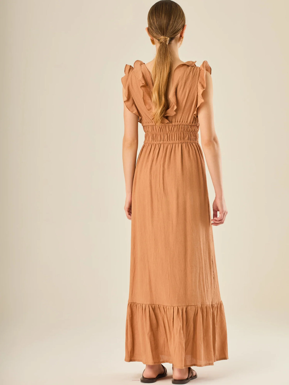 Vestido largo sin mangas con escote en "V" profundo y un diseño con volantes que recorren tanto los tirantes como la parte frontal del busto y la falda. La cintura está fruncida con elástico para dar definición y comodidad, mientras que la falda fluye suavemente con un detalle de volante en el dobladillo, aportando movimiento y un aire femenino al conjunto.

Detalles:

Color: Cafe