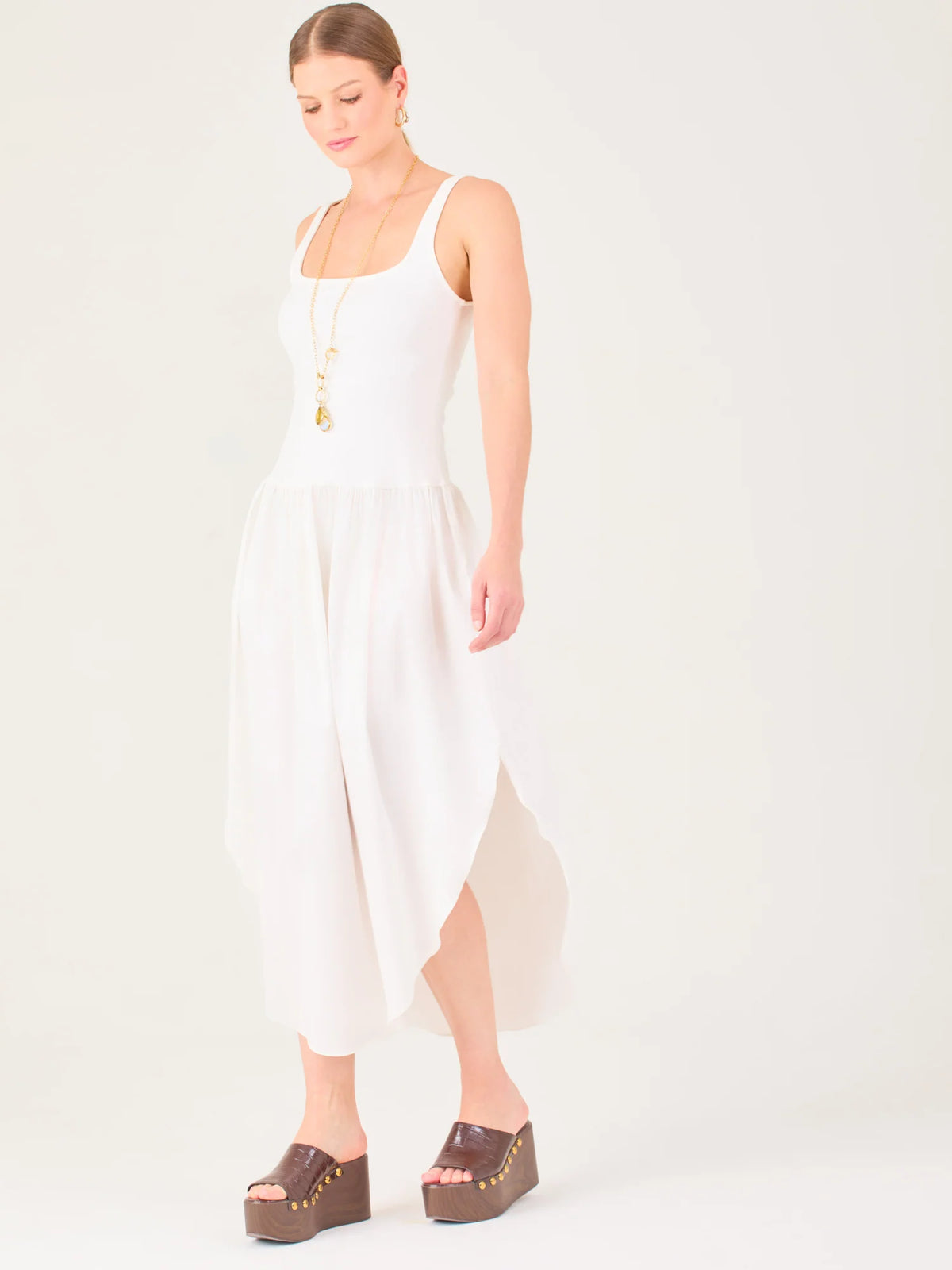 Vestido midi de líneas limpias con tirantes anchos y escote recto. Cuerpo suavemente entallado que cae a una cintura baja fruncida y una falda amplia con bajo redondeado asimétrico tipo pétalo. Una pieza fresca y sofisticada para elevar looks de día o de tarde

Detalles:

Color: Blanco

Material: 95% Poliéster 5% Elastómero 